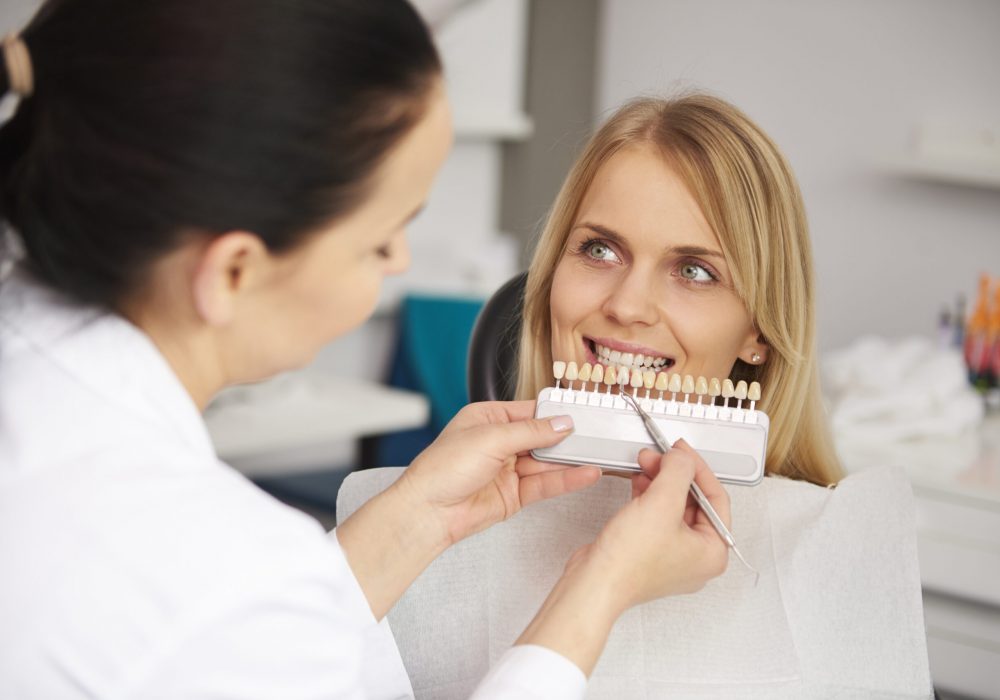 Dentist choosing color teeth from palette