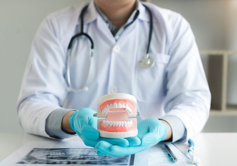 Dentist holding dentures in office room.