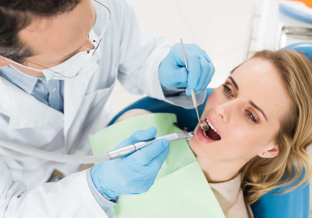 Female patient at dental procedure using dental drill in modern dental clinic